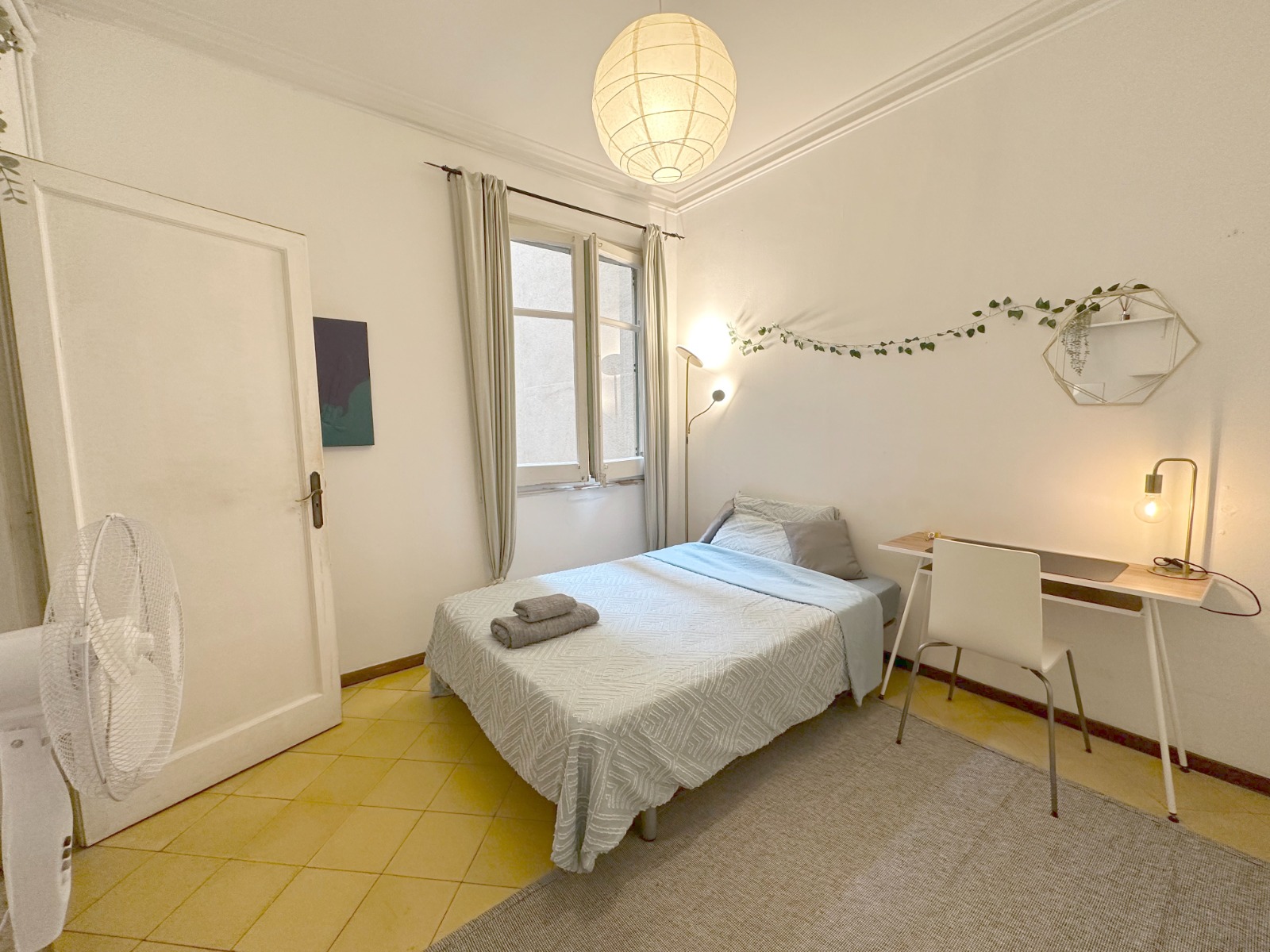 Habitación luminosa de Borrell Coliving con lámpara de papel y guirnalda vegetal